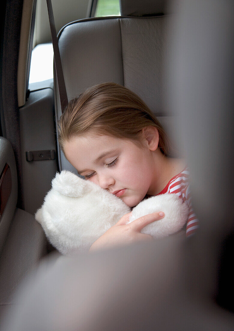 Portrait of young girl sleeping and cuddling teddy bear\n