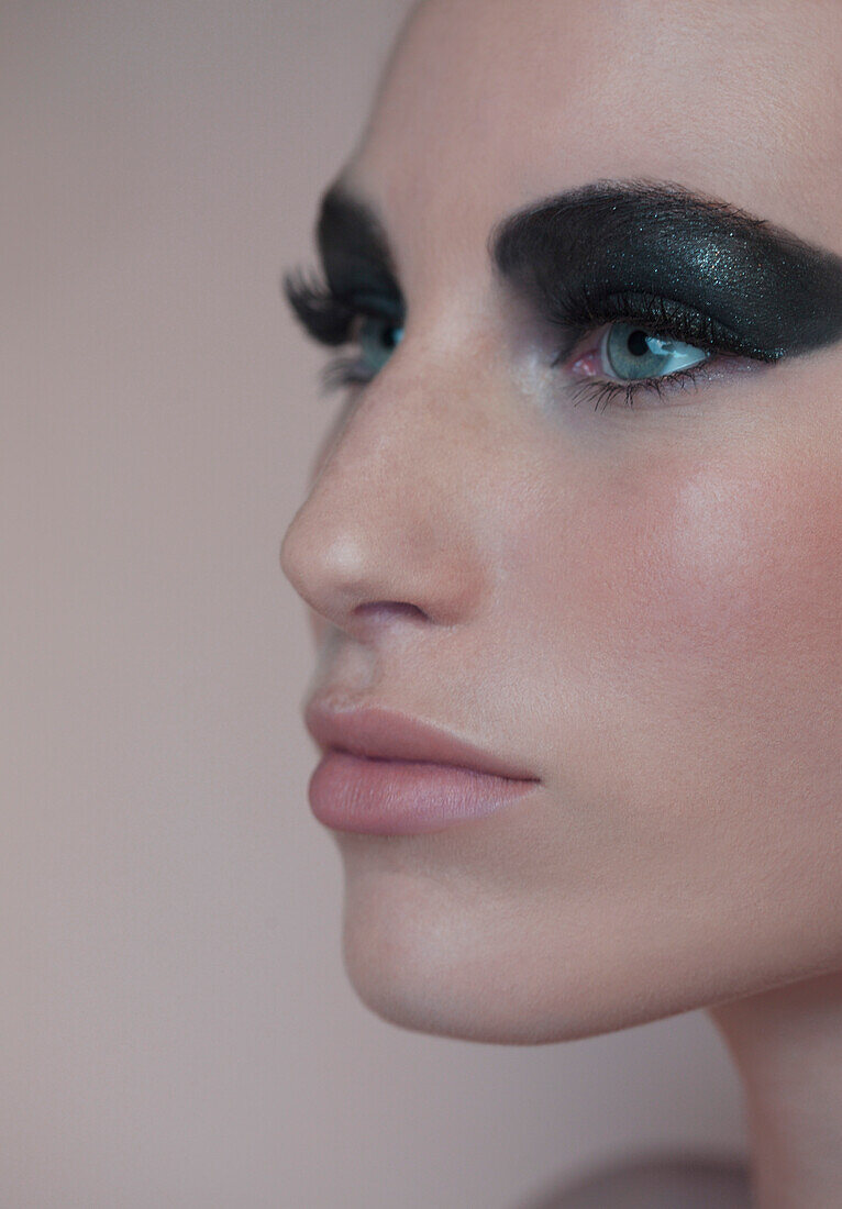 Close up profile of beautiful young woman with black eyeshadow\n
