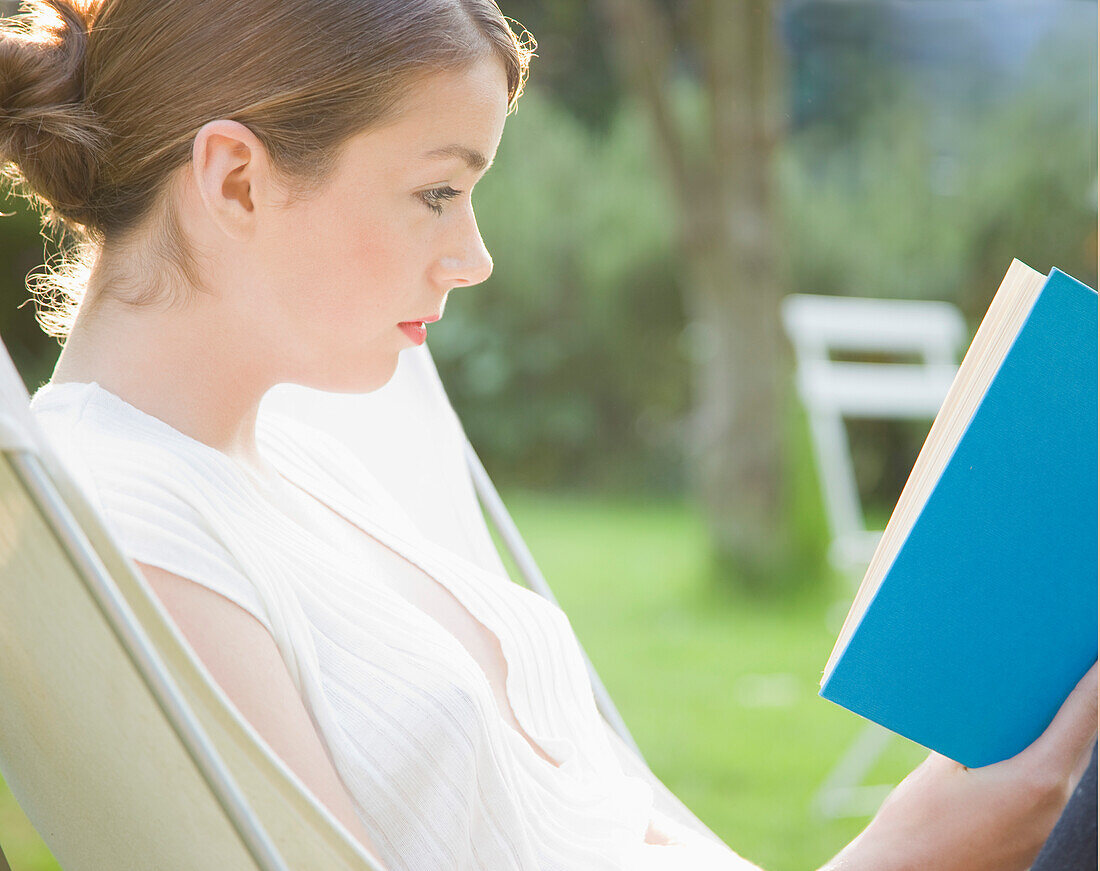 Teenaged girl sitting and reading a book\n