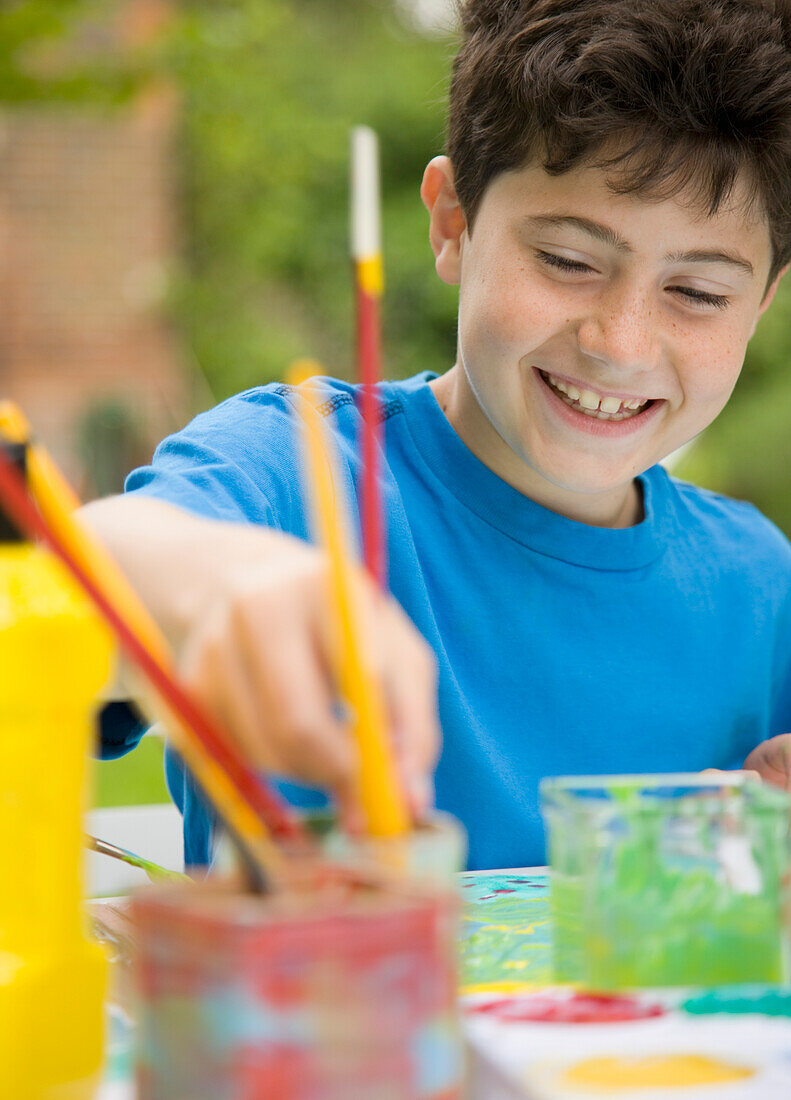 Young boy painting and smiling\n