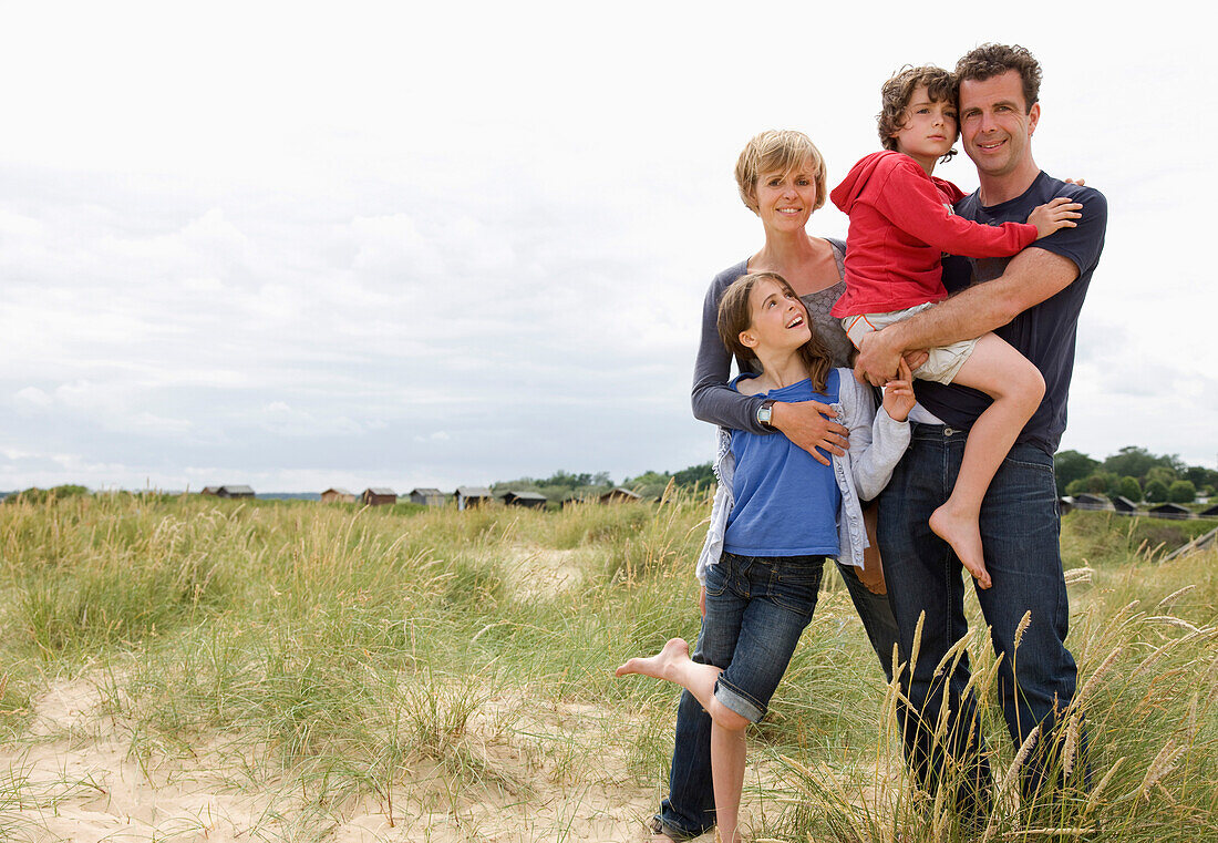 Portrait of family standing on a beach smiling\n