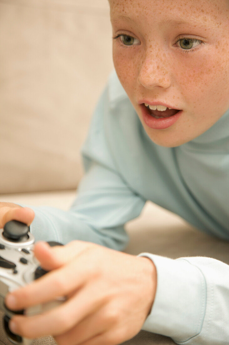 Close up of a young boy playing and holding a video game control\n