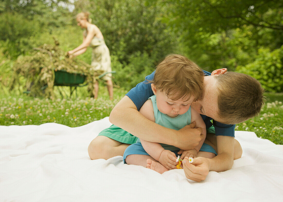 Kleiner Junge sitzt im Garten und umarmt und küsst seinen kleinen Bruder