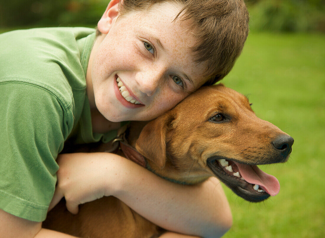 Junger lächelnder Junge umarmt seinen Hund