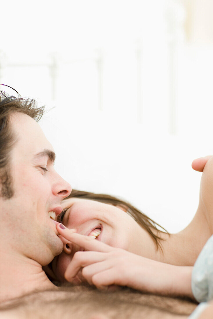 Close up of couple in bed laughing\n