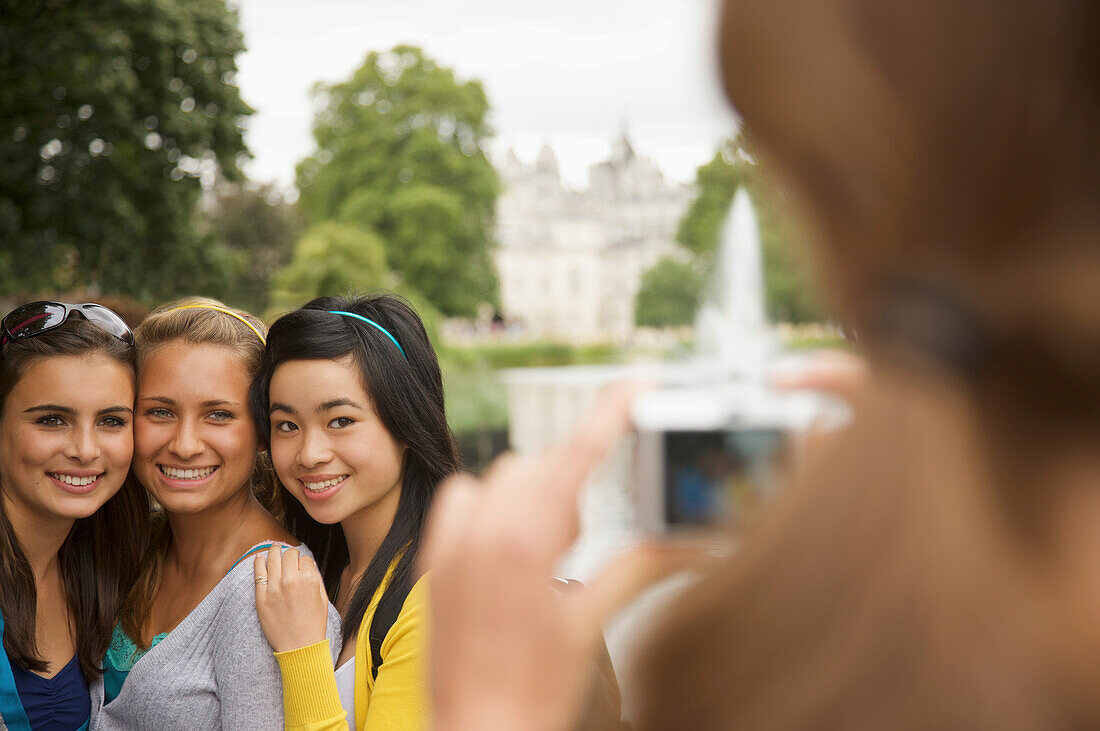Rückenansicht einer Frau, die drei Mädchen im Teenageralter fotografiert