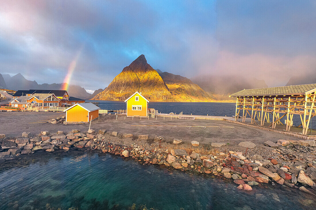 Panoramablick aus der Luft auf die traditionelle Rorbu und den Berg Olstind unter dem Regenbogen, Sakrisoy, Reine, Lofoten, Nordland, Norwegen, Skandinavien, Europa