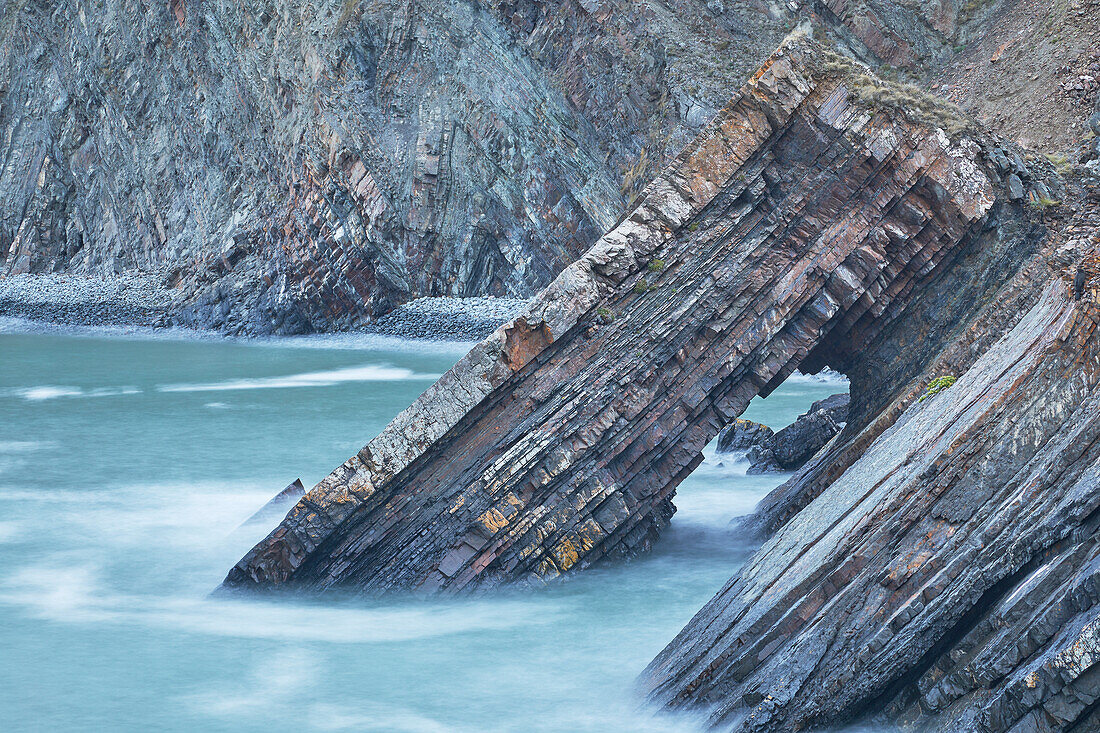 A dusk view of a rock arch formed from layers of sedimentary rocks, at Hartland Quay, on the Atlantic coast of Devon, England, United Kingdom, Europe\n