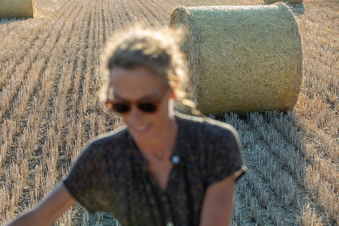 Bales of straw on field stubble at summer, woman on foreground\n