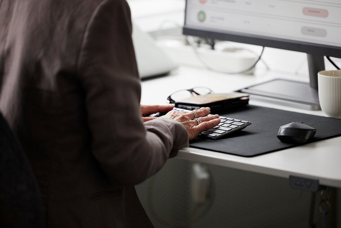 Mid section of woman in office using desktop PC\n