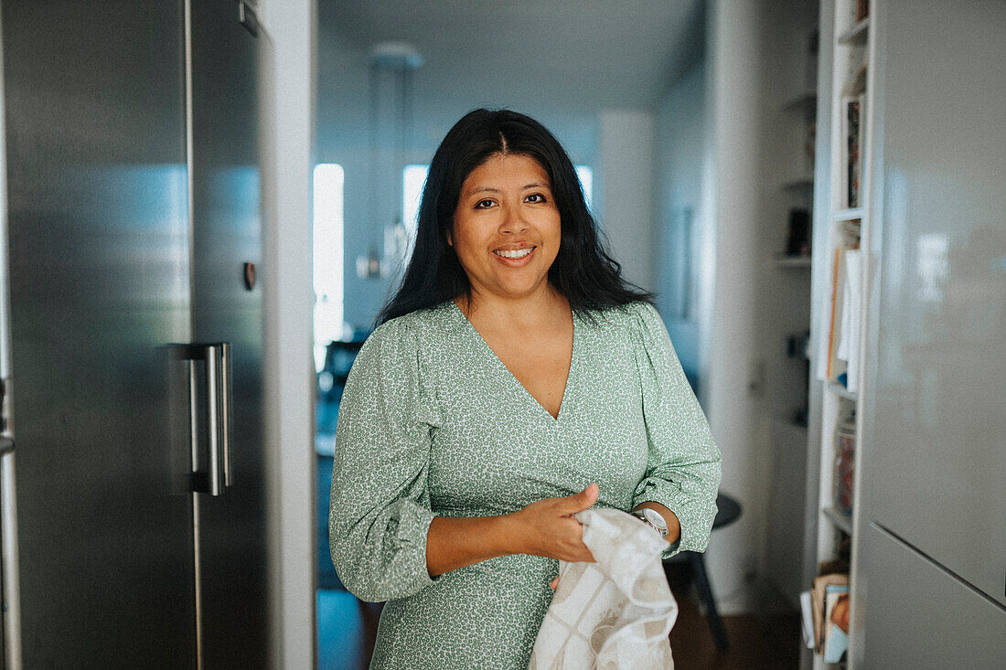 Portrait of smiling woman doing housework in kitchen\n