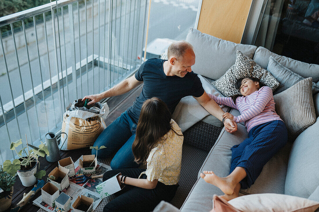 Vater und Töchter gemeinsam beim Pflanzen von Setzlingen auf dem Balkon