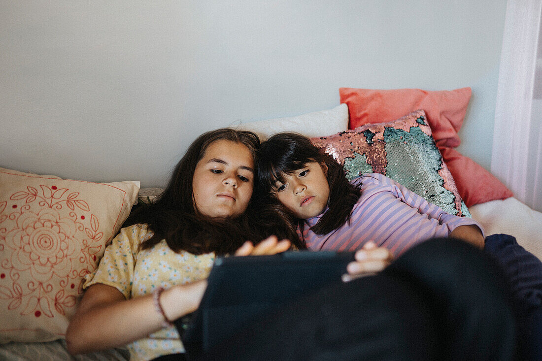 Sisters bonding over surfing internet on tablet together\n