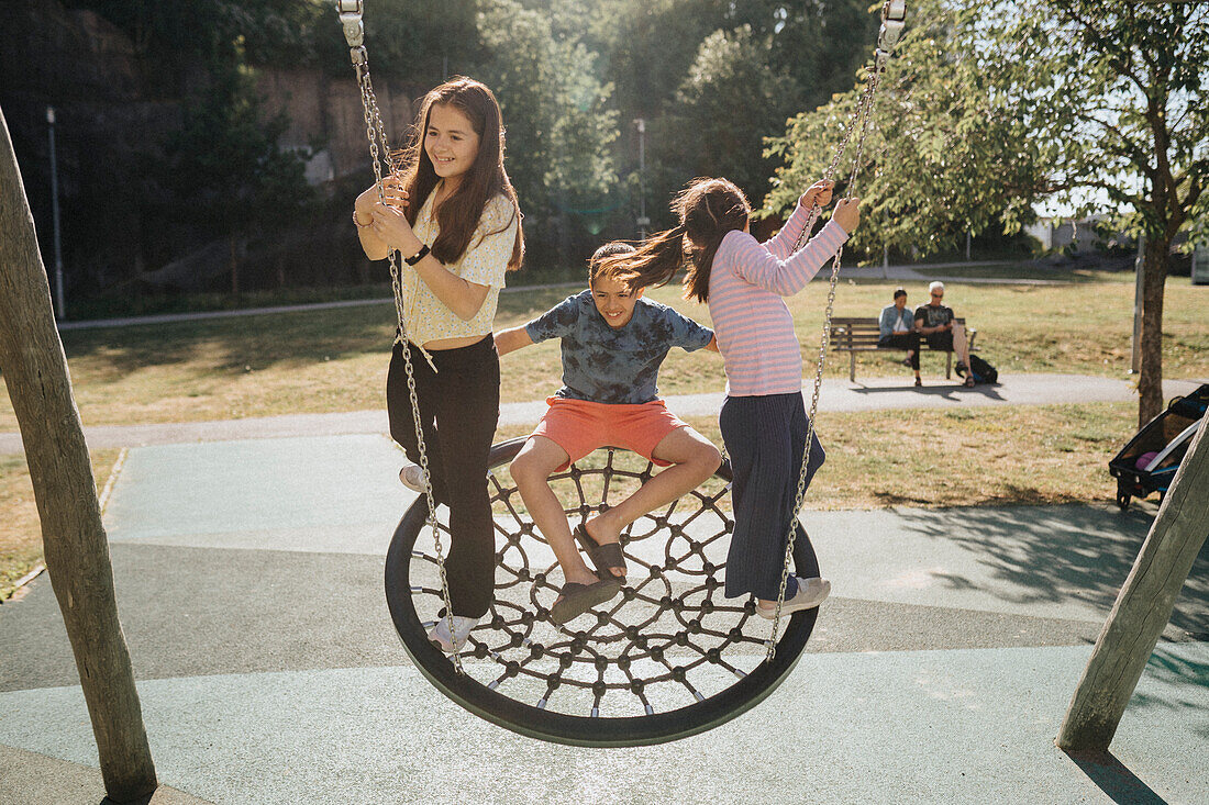 Geschwister haben Spaß beim Schaukeln auf dem Spielplatz