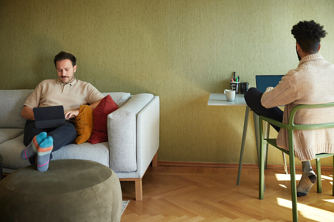 Homosexual couple relaxing in living room\n