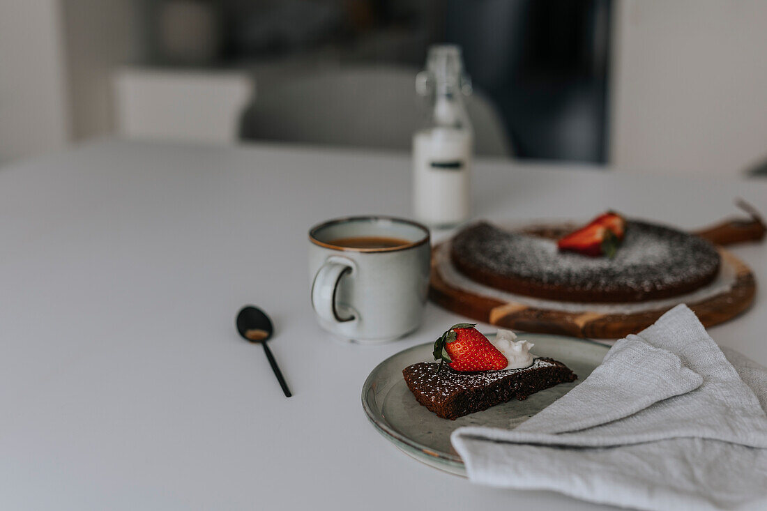 Freshly baked chocolate cake with strawberries and cream on table\n