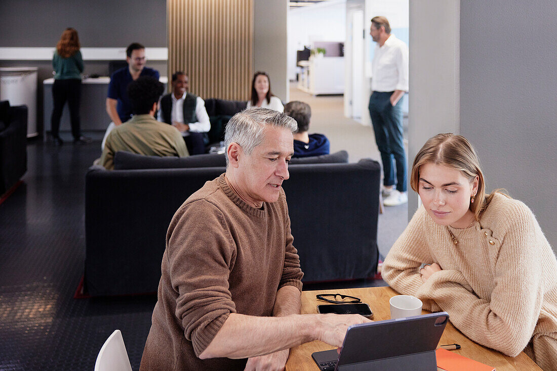 Two professionals working together in office cafeteria\n