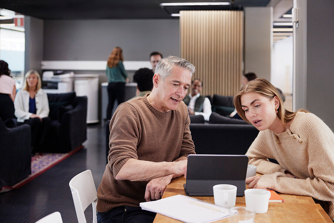 Two professionals working together in office cafeteria\n