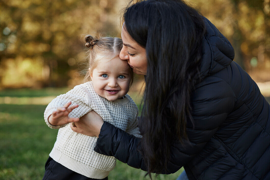 Happy mother hugging daughter in park\n