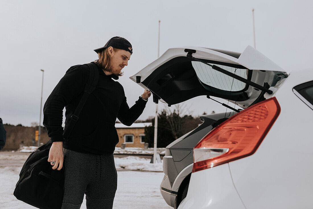 Man packing bag in car after workout in gym\n