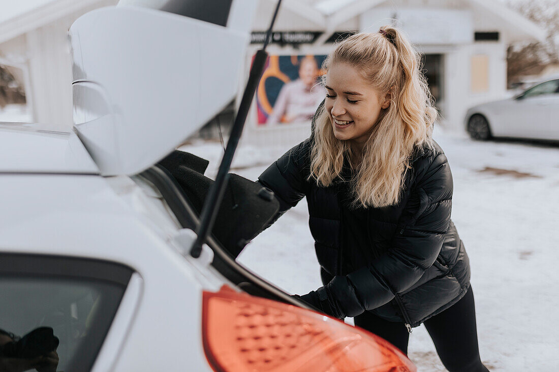 Junge Frau packt Tasche im Auto nach dem Training im Fitnessstudio