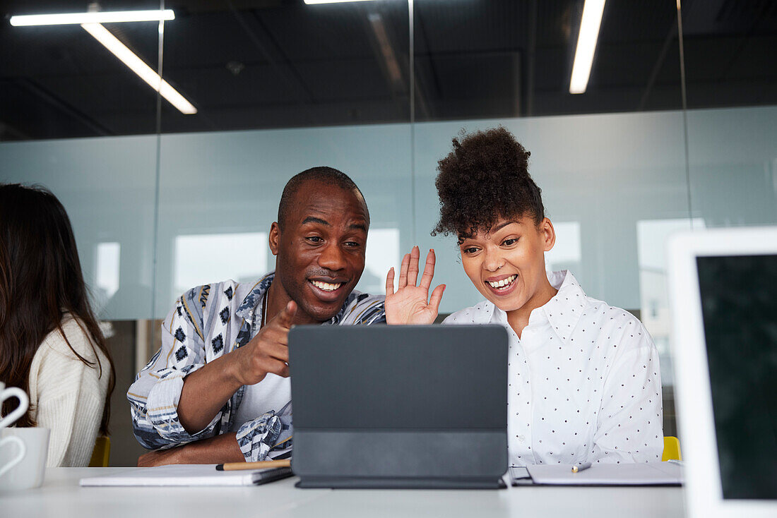 Smiling coworkers sitting at business meeting and using digital tablet\n