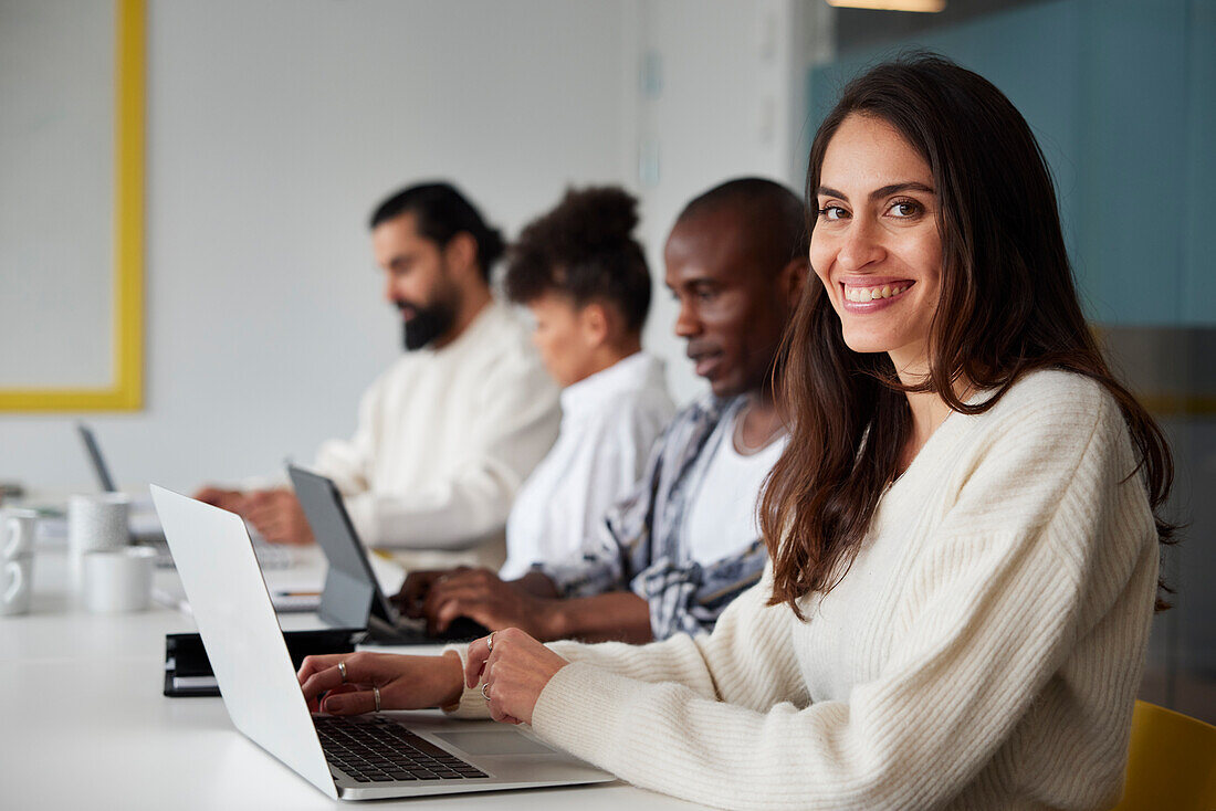 Smiling woman sitting during business meeting and looking at camera\n