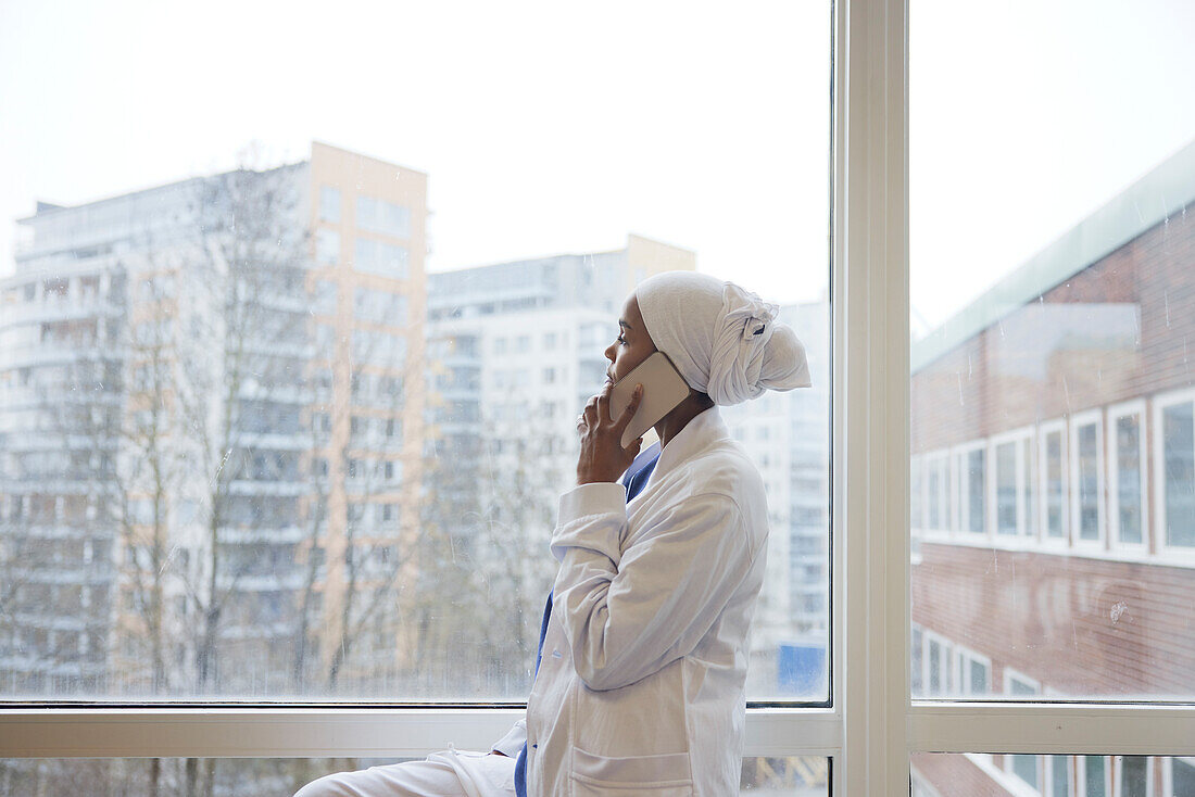 Female doctor looking away and talking via cell phone\n