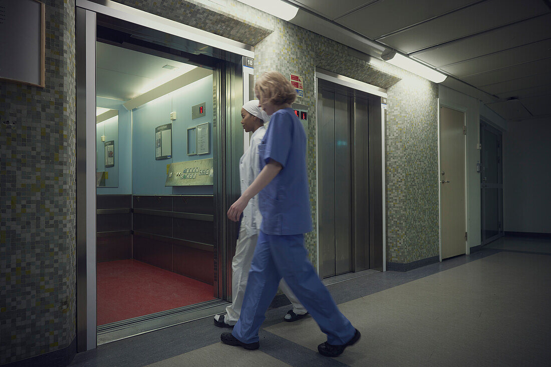 Female doctors entering open lift in hospital\n