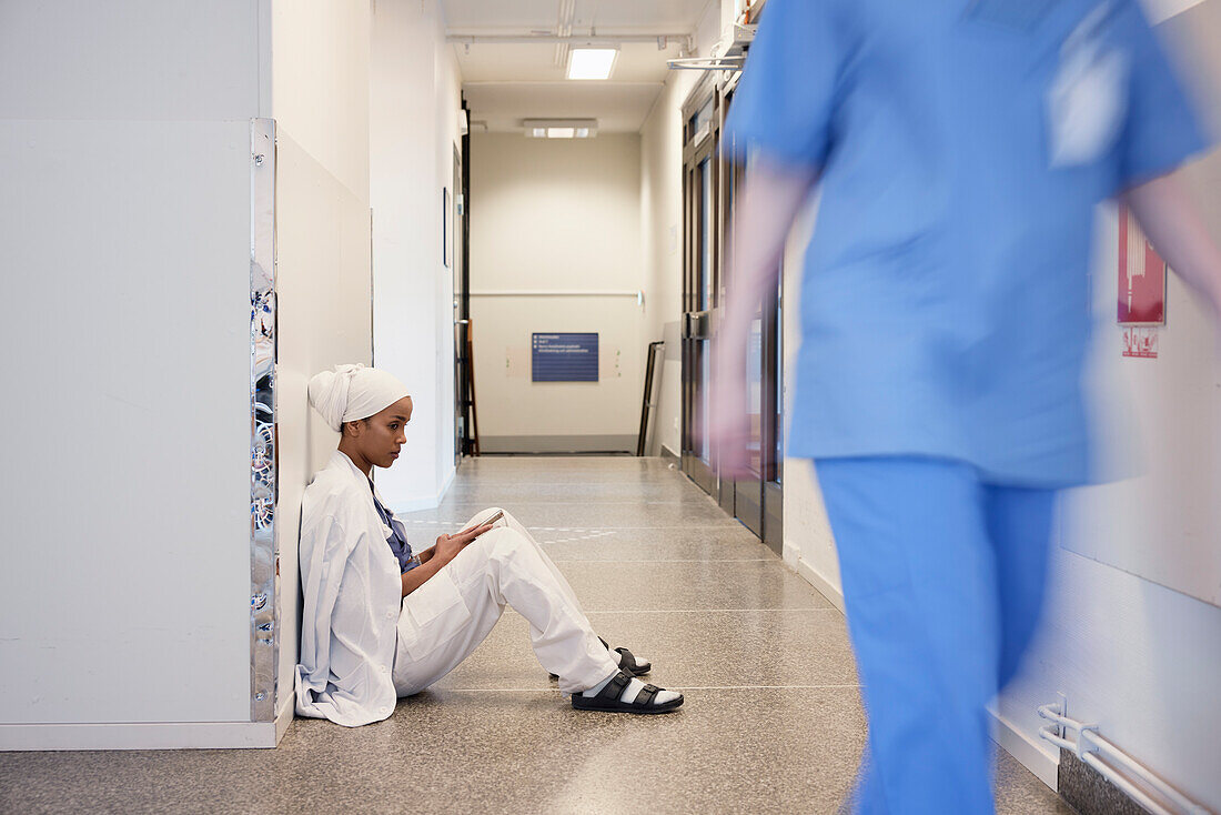 Female doctor sitting on hospital corridor floor\n