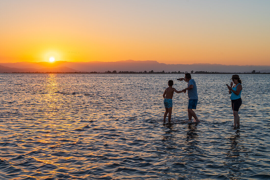 People enjoying sunset at Trabucador beach, Ebro Delta, Tarragona, Spain\n