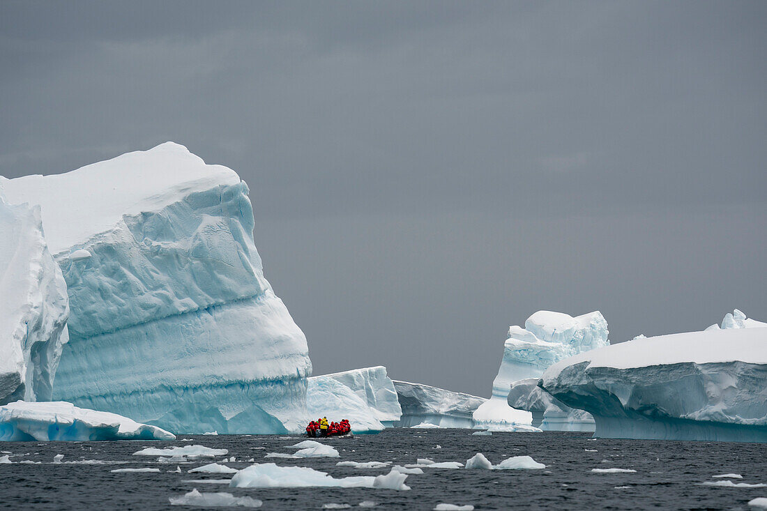 Touristen in einem Schlauchboot erkunden die Pleneau-Insel in der Antarktis.