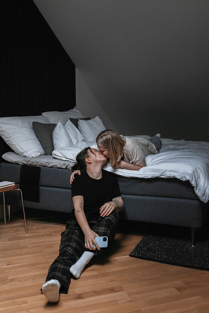 Homosexual female couple kissing in bedroom\n