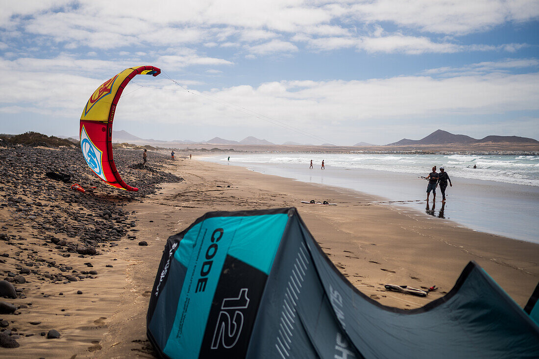 Kite-Surfer am Strand von Famara (Playa de Famara), 6 km langer goldener Sandstrand im Naturpark des Chinijo-Archipels, zwischen dem Fischerdorf La Caleta de Famara und dem Fuß der beeindruckenden Klippen von Famara, Lanzarote, Kanarische Inseln, Spanien