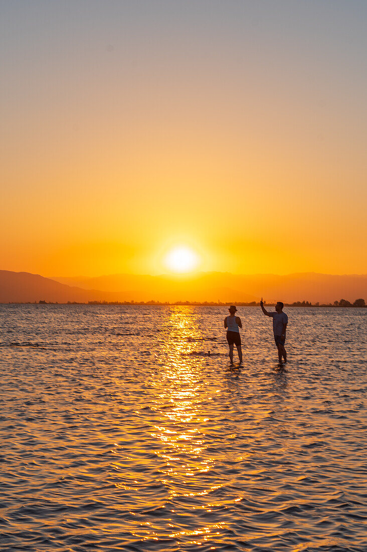 Menschen genießen den Sonnenuntergang am Strand von Trabucador, Ebro-Delta, Tarragona, Spanien