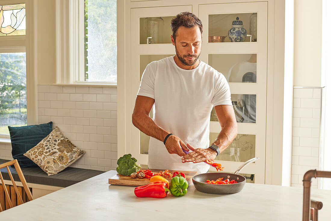 Man cutting vegetables in kitchen\n