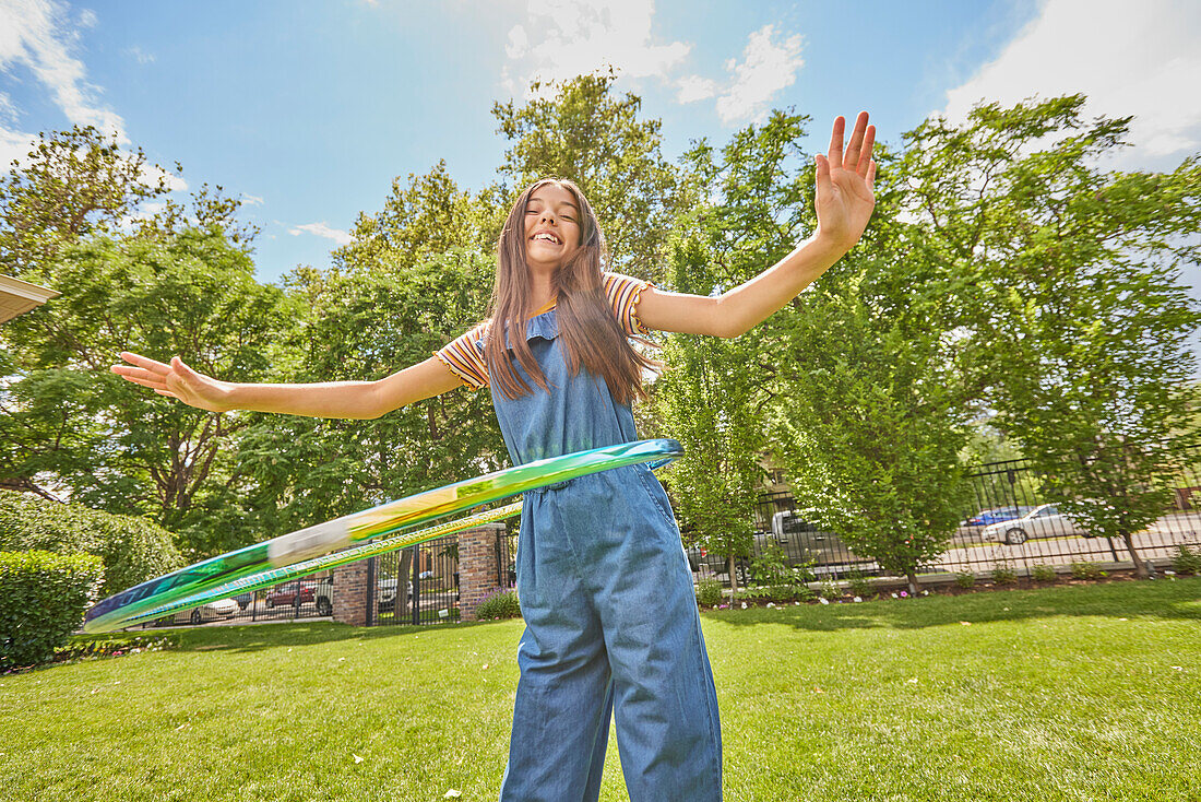 Lächelndes Mädchen (12-13) spielt mit Hula-Hoop-Reifen im Park