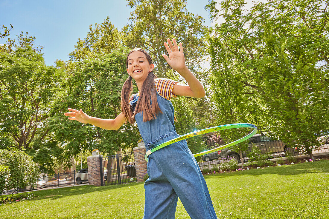 Lächelndes Mädchen (12-13) spielt mit Hula-Hoop-Reifen im Park