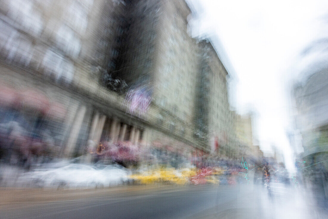 Blurred image of cars and people on city street\n