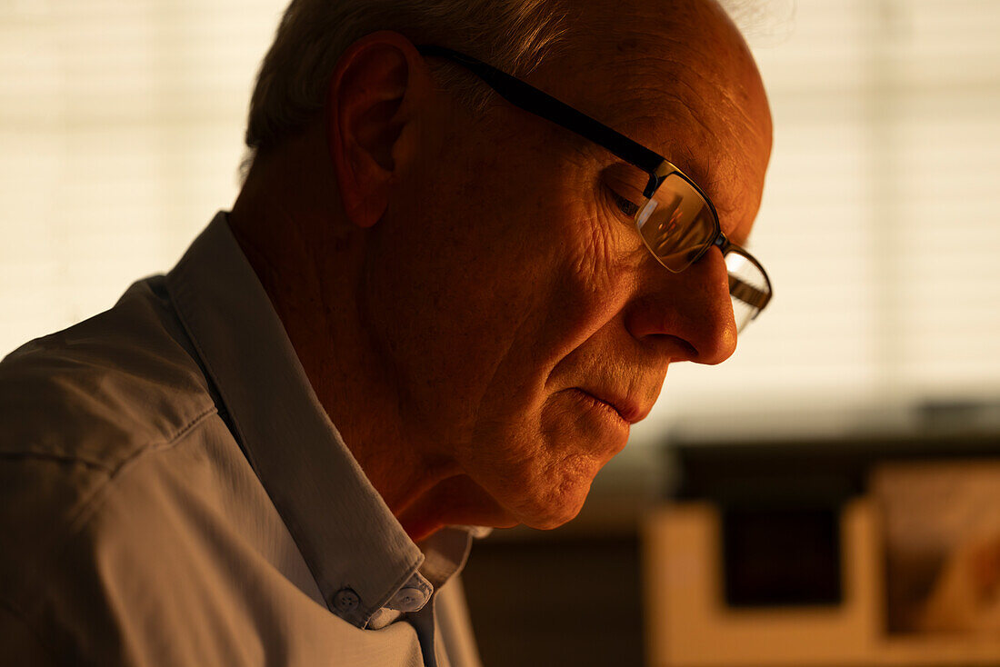 Portrait eines nachdenklichen älteren Mannes, der auf sein Haus hinunterblickt