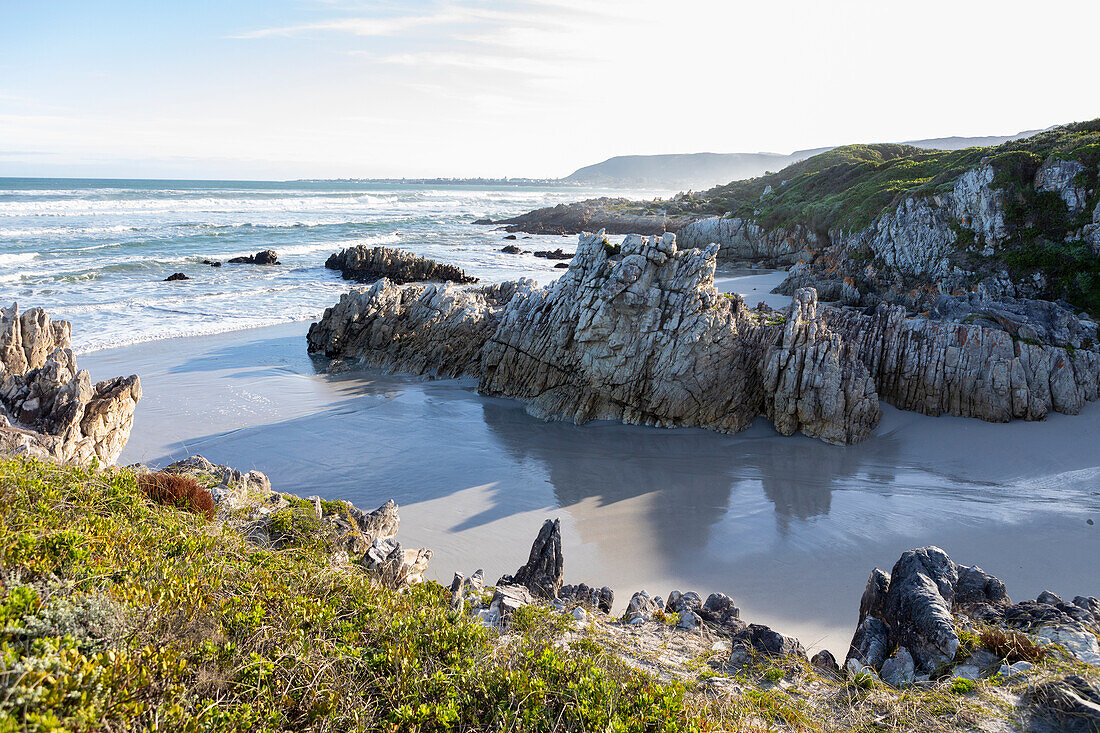 South Africa, Hermanus, Rocky coastline with Atlantic Ocean in Voelklip Beach on sunny day\n