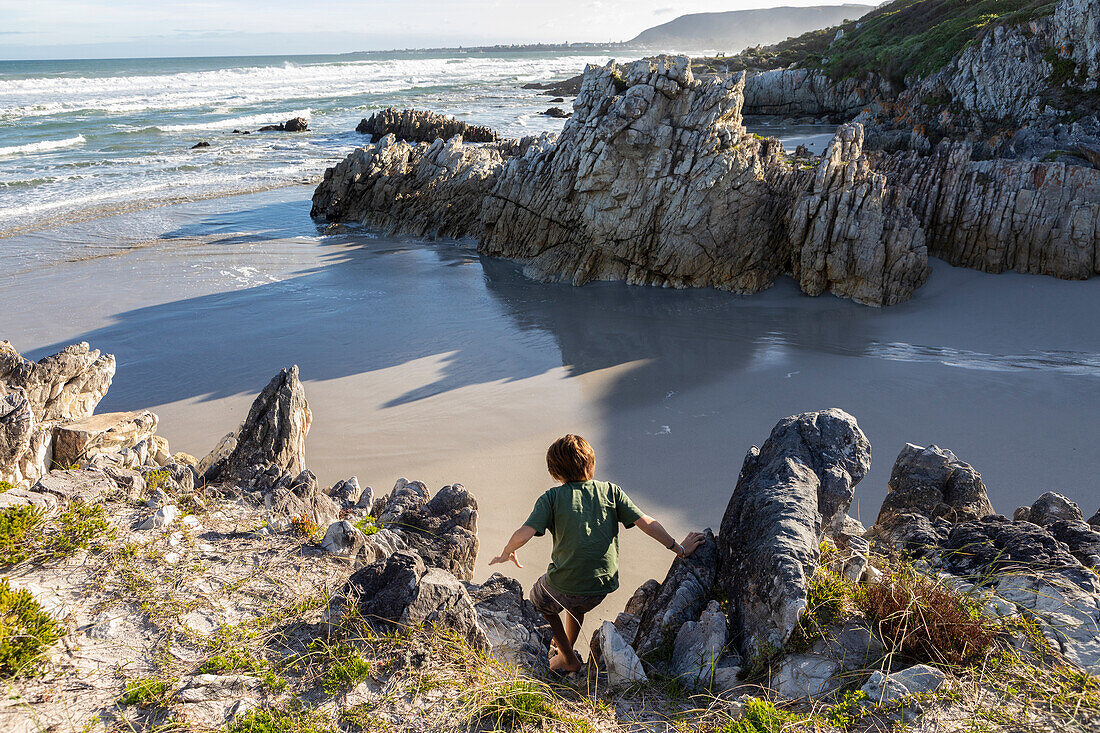 South Africa, Hermanus, Boy (10-11) exploring rocky coastline in Voelklip Beach\n