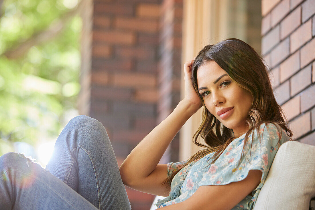 Portrait of mid adult woman relaxing on sofa on patio\n