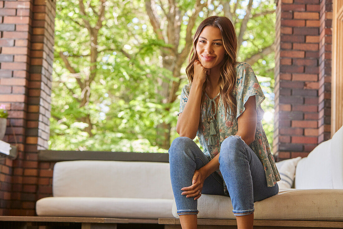 Portrait of mid adult woman relaxing on sofa on patio\n