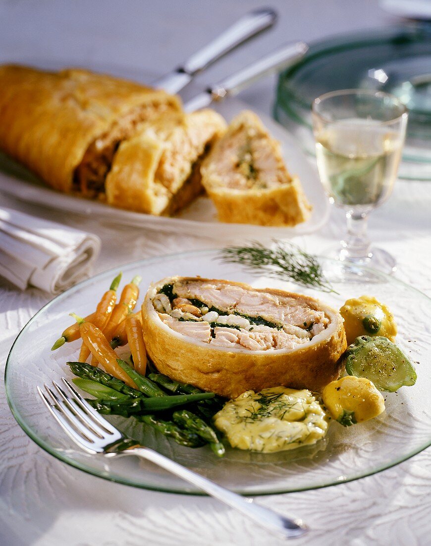 Stück Lachsstrudel mit Gemüse auf Glasteller