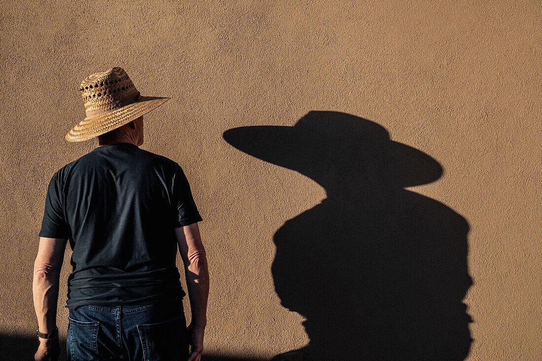 Man in hat casting shadow on wall\n