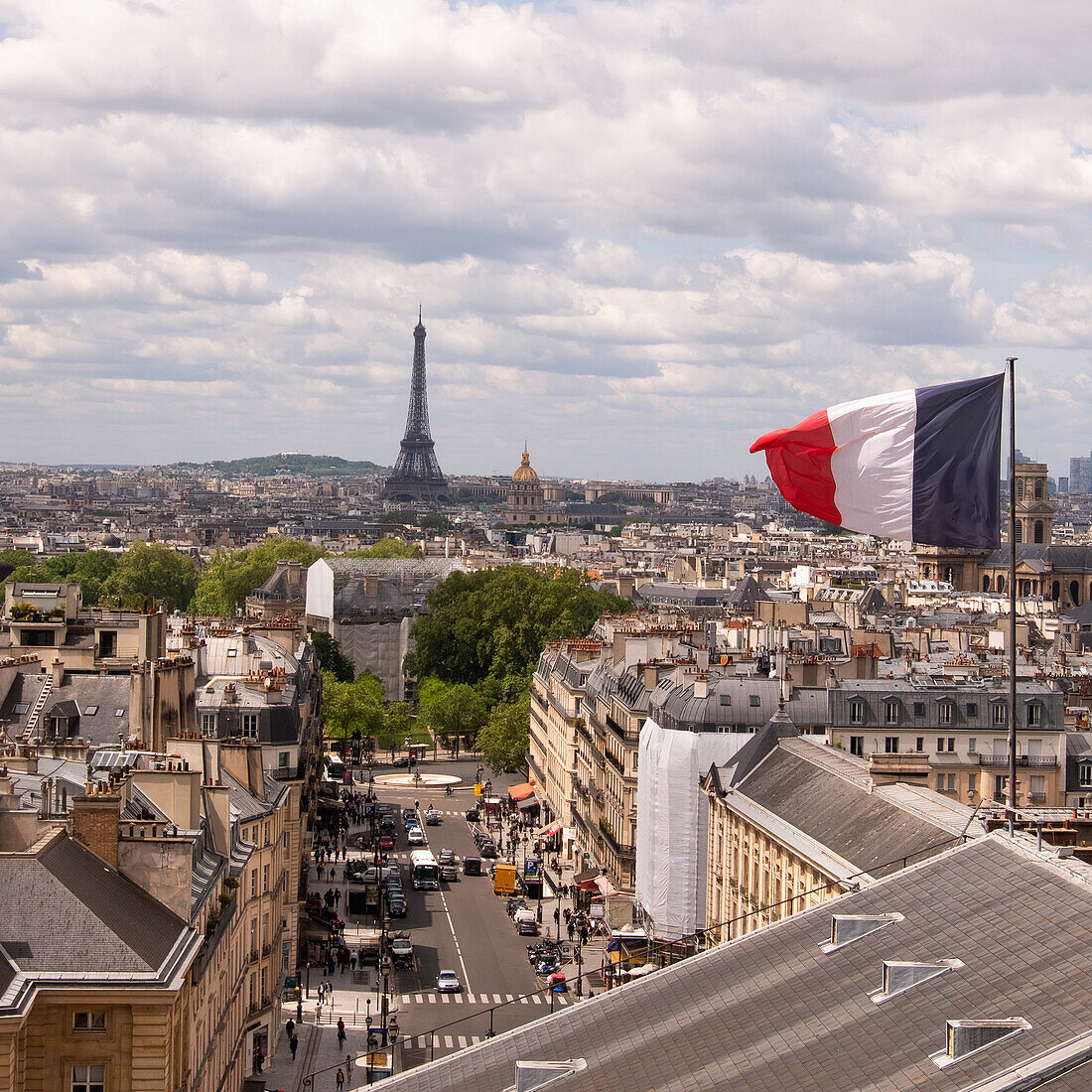 France, Paris, French flag on building roof, Eiffel tower in background \n