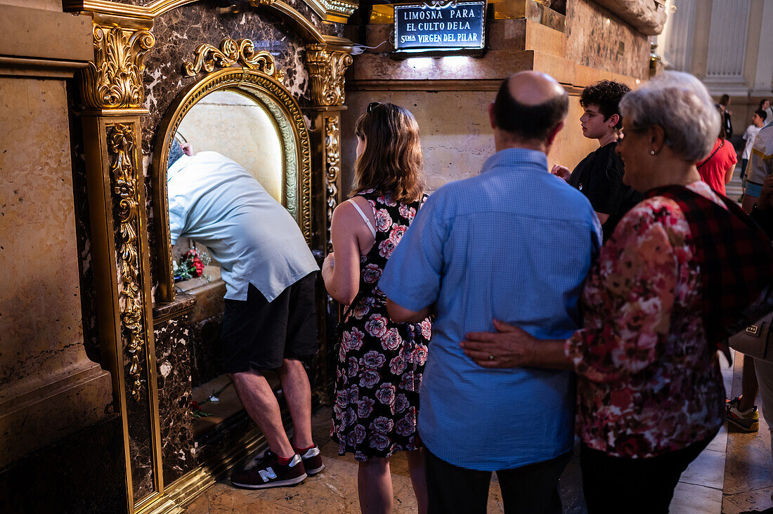 Worshipers kissing the pillar inside the Cathedral-Basilica of Our Lady of the Pillar during The Offering of Flowers to the Virgen del Pilar, the most important and popular event of the Fiestas del Pilar held on Hispanic Day, Zaragoza, Spain\n