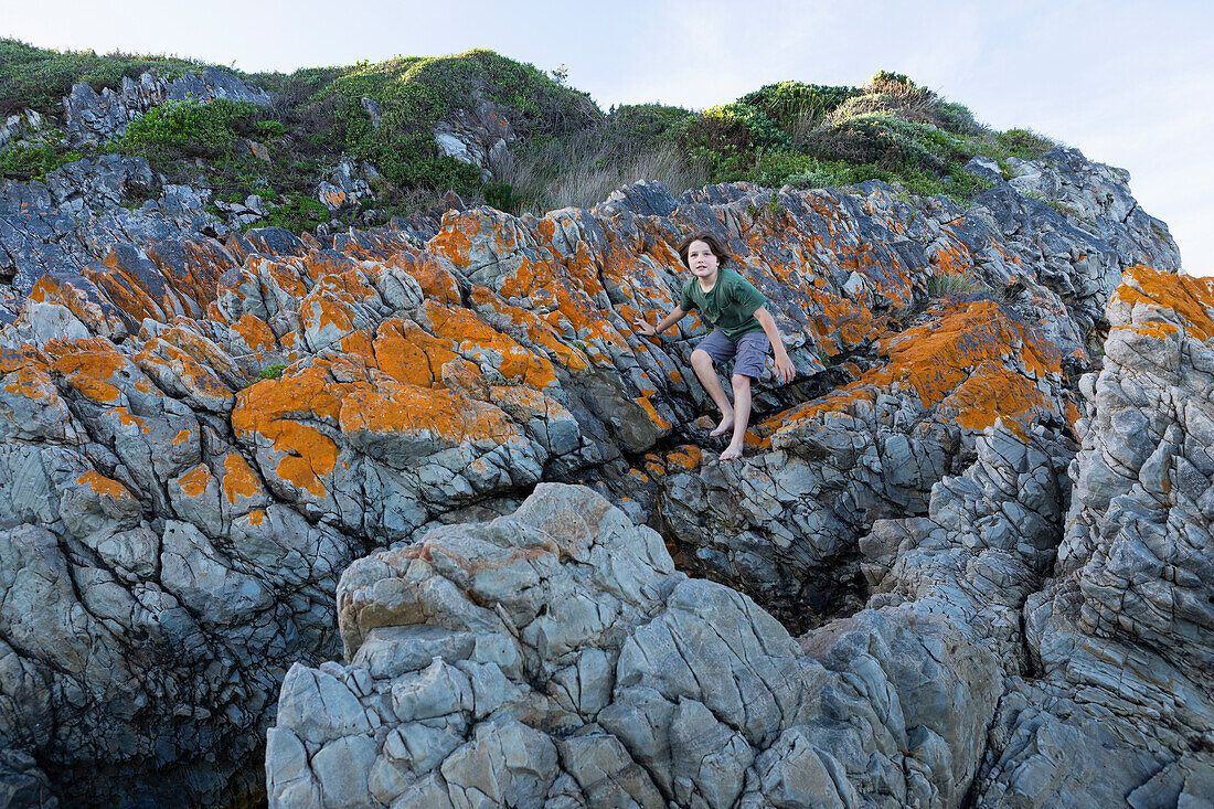 Boy (10-11) standing on rock in Voelklip Beach\n