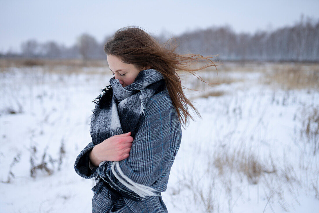 Porträt einer frierenden Frau auf einer verschneiten Wiese